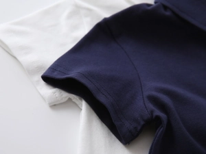 Detailed close-up of double-needle stitching on navy and white cotton polo shirts