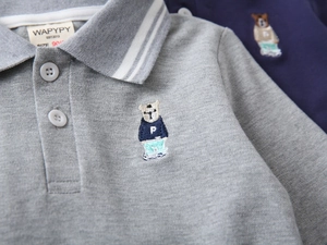 Macro shot of bear embroidery and breathable pique fabric on a boys' grey polo shirt