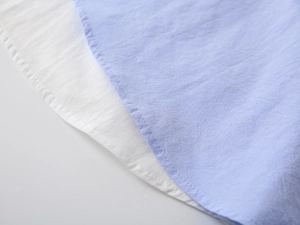 Detail of light blue and white breathable cotton-linen shirts with curved hem and texture