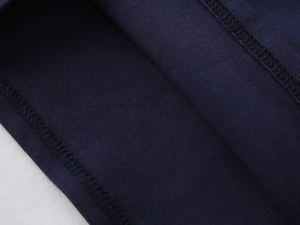 Macro view of dark blue cotton knit fabric showing precise overlock stitching detail