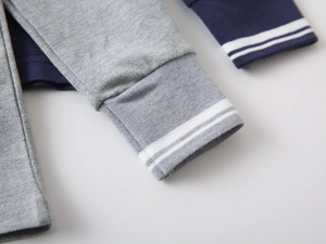 Detail of ribbed cuffs with dual white stripes on grey and navy cotton long sleeve polo shirts