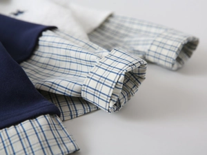 Dettaglio dei polsini a costine a strati e maniche di camicia a quadri blu per ragazzi