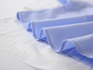 Macro view of light blue and white pleated fabric with precise stitching on boy's shirt