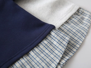Dettagli ravvicinati della felpa da bambino a strati con maglia blu, cotone e trama a quadri