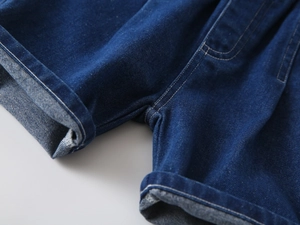 Detail view of boys' navy blue denim shorts showing double-stitched seams and folded hem
