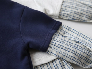 Dettaglio maglione bambino con finto colletto di camicia a quadri e polsini a costine
