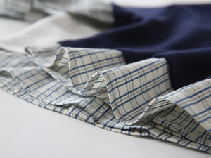 Dettaglio del tessuto blu scuro cucito con balze a quadri blu e bianchi sulla maglia bimbo