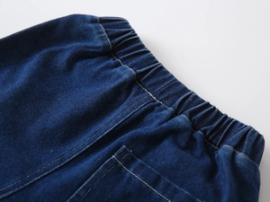 Close-up of boys' dark blue denim shorts featuring elastic waistband and pocket stitching