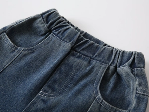 Detail of boys denim jeans showing elastic waistband and stitching on washed blue fabric