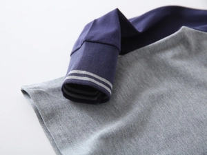 Dettaglio dei polsini a coste blu navy con strisce grigie su una polo per bambini