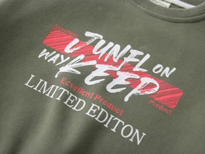 Detail of olive green boy's sweatshirt featuring premium cotton texture and printed graphics