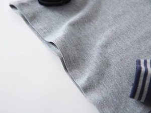 Dettaglio del tessuto a maglia grigia con polsini a costine a righe blu navy e grigio