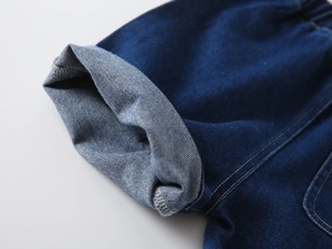 Detail of dark blue denim boys' shorts with cuffed hems and white contrast stitching
