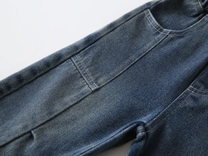 Detail of heavy-duty washed blue denim fabric with contrast stitching on boy's retro jeans