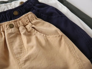 Detail view of cotton shorts showing elastic waist with metal button in multiple colors