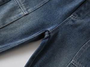 Detail of reinforced stitching and washed denim fabric on boys' vintage style jeans