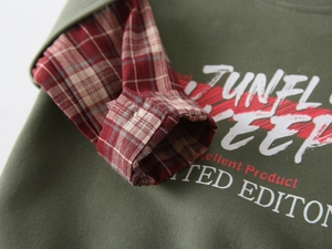 Detail of boys' olive green hoodie with red checkered sleeve patchwork and print