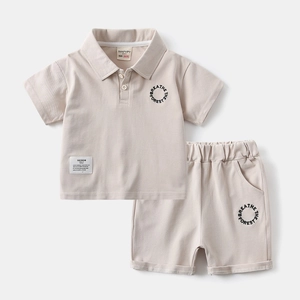 Flat lay detail of kids beige cotton polo shirt and shorts set with forest embroidery