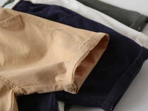 Detail of rolled cuffs on multi-color cotton shorts for boys in khaki, navy, and green