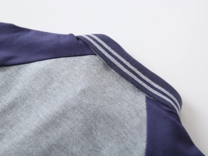 Dettaglio della polo con colletto a costine a righe e cuciture precise in grigio e blu