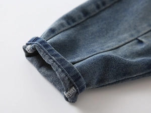 Close-up of boys denim jeans showing cuffed hem detail and white contrast stitching