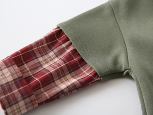 Detail of the stitched cuffs showing sage green fabric and red plaid shirt sleeve insert