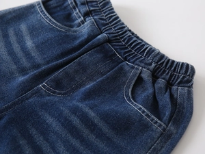 Detail of boys denim trousers with elastic waistband and double stitching on dark blue fabric