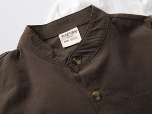 Macro detail of the dark brown boy's linen shirt collar, buttons, and fabric texture