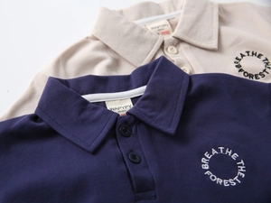 Detail of boys' polo shirt collar with Breathe the Forest embroidery and button placket