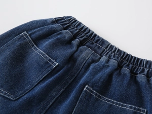 Detail view of boys' dark blue denim pants showing elastic waistband and white contrast stitching