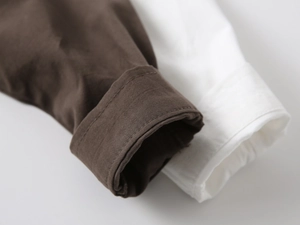 Close-up of boys long sleeve shirt cuffs in brown and white with double-stitched cotton fabric