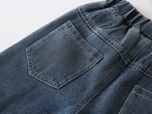 Detail of boys' dark blue denim pants showing elastic waistband and back pocket texture