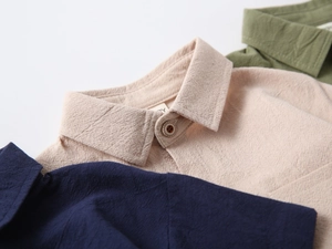 Detail of toddler shirt collars showing beige, navy, and green cotton linen texture