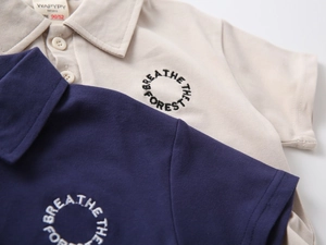 Close-up of boys' polo shirt collar with forest embroidery and high-quality pique fabric