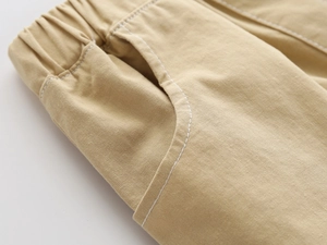 Close-up of khaki cotton shorts featuring elastic waistband and white contrast stitching detail