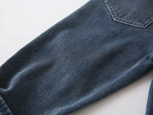 Close-up of boys vintage washed denim fabric with detailed twill texture and stitching