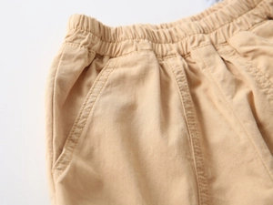 Detail of khaki cotton shorts showing elastic waistband and side pockets for boys