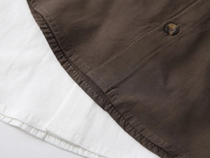 Detail of boys' V-neck shirt showing brown and white patchwork fabric with amber button