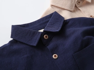 Detail of cotton linen shirt fabric showing navy blue texture and vintage wooden buttons