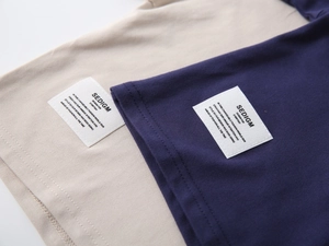 Close-up of knit fabric texture and logo label on boys' beige and navy polo shirts