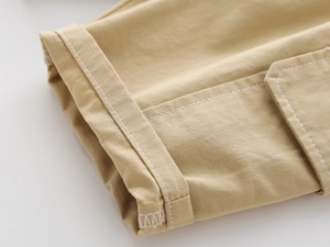 Detail of khaki twill cotton boy's shorts featuring white contrast stitching and cuff fold