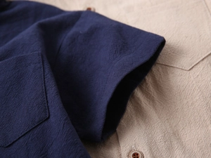Detail shot of navy short sleeve shirt featuring textured fabric and pocket stitching