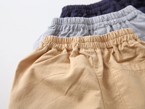 Detail of elastic waistbands on cotton boys' shorts in navy, gray, and khaki colors