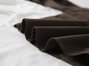 Macro detail of dark brown pleated fabric texture and stitching on boys' V-neck shirt