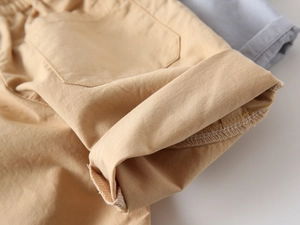 Detail view of khaki boy's shorts showing premium cotton fabric and rolled cuffs