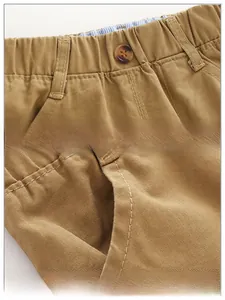 Detail of khaki twill cotton boy's pants featuring elastic waistband and resin button