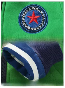 Détail de veste verte garçon avec broderie étoile et poignets rayés bleu et blanc
