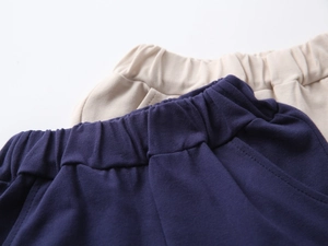 Detail of elastic waistbands on navy and beige cotton shorts with precise stitching