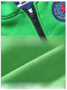 Détail du pull en maille verte avec fermeture éclair noire et écusson étoile brodé