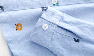 Detailed macro view of oxford fabric texture and bear print on the blue shirt cuff
